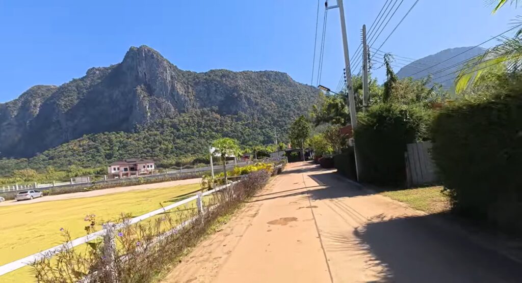 Rural road leading toward a mountain with a natural opening in Sa Kaeo, Thailand
