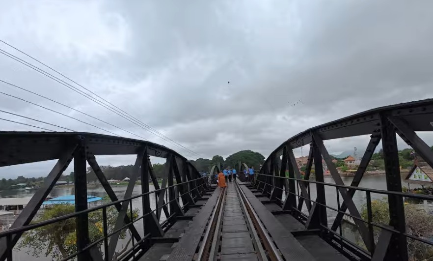 Walking across the historic River Kwai Bridge in Kanchanaburi Thailand