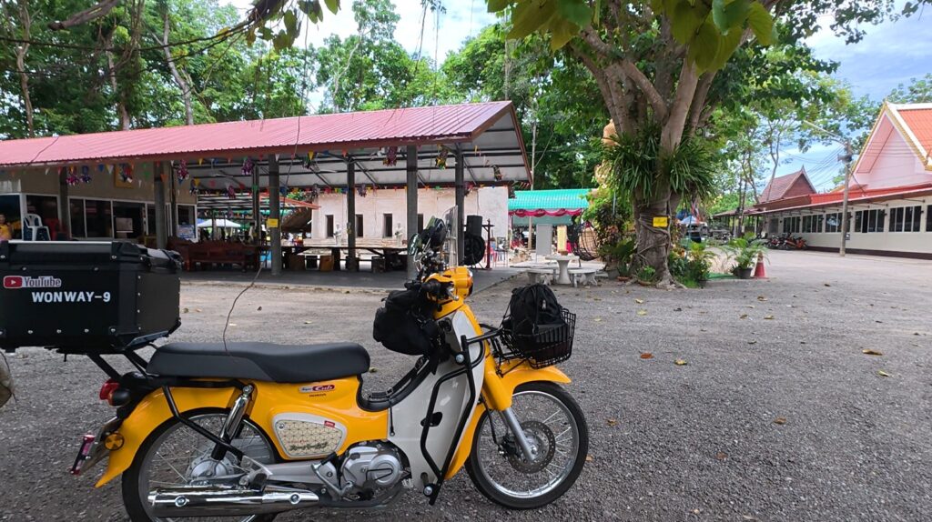 Yellow Honda Cub parked beside the old ubosot of Wat Khao Bot in Rayong