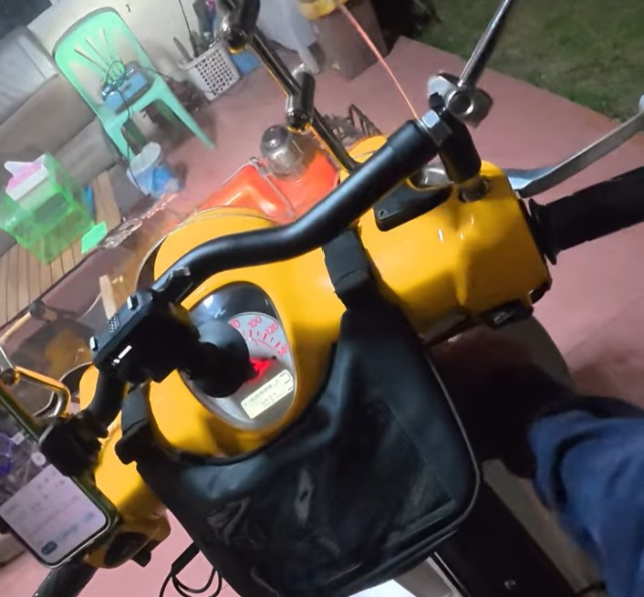 Rider resting a hand on the Honda Cub after returning home