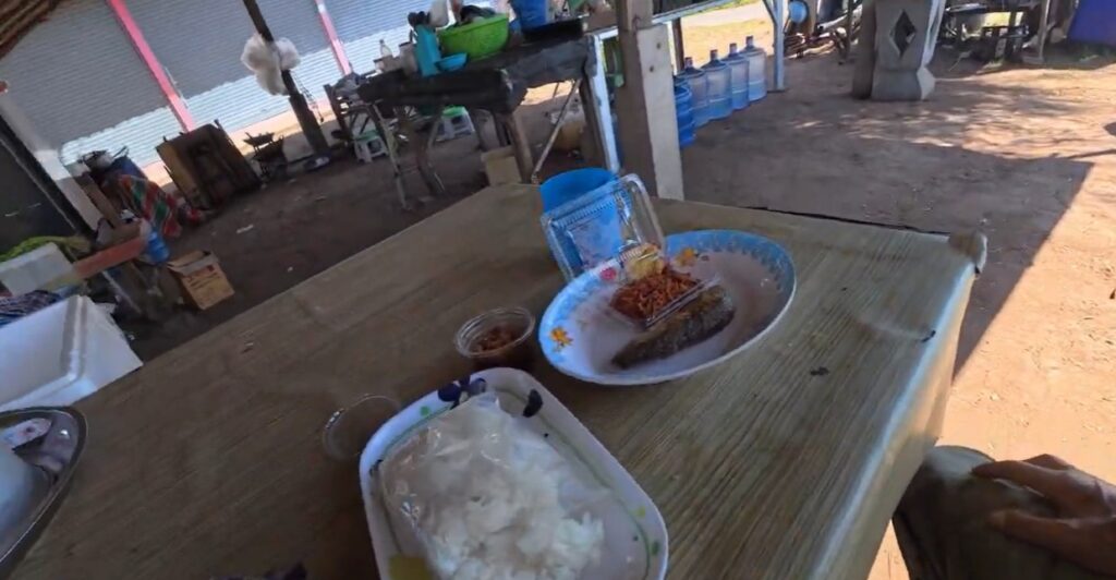 A beginner rider resting after a country meal at a small village shop in Isan