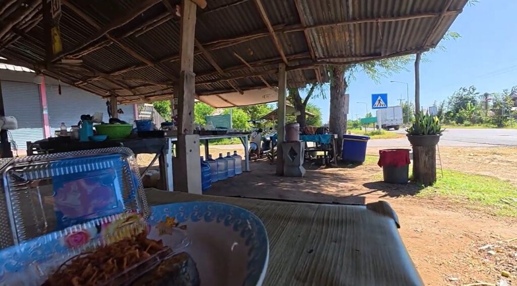 A motorcycle ready to continue the journey from a rural village toward Roi Et