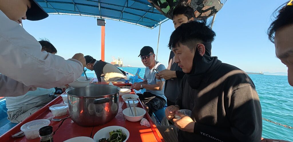 Friends sharing food and drinks during a sea fishing trip