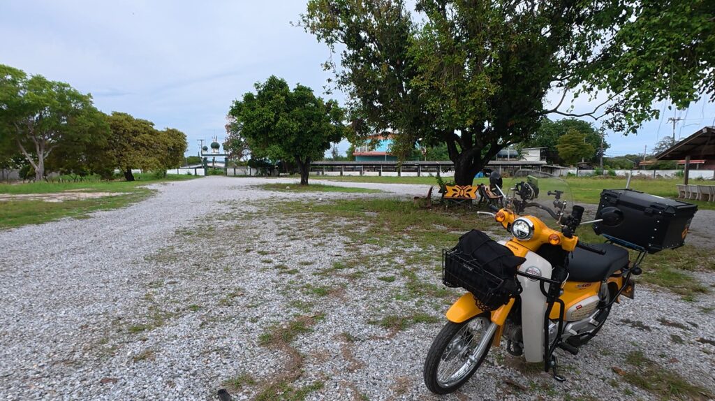 Honda Cub parked beneath a tree near a Muslim community in Rayong