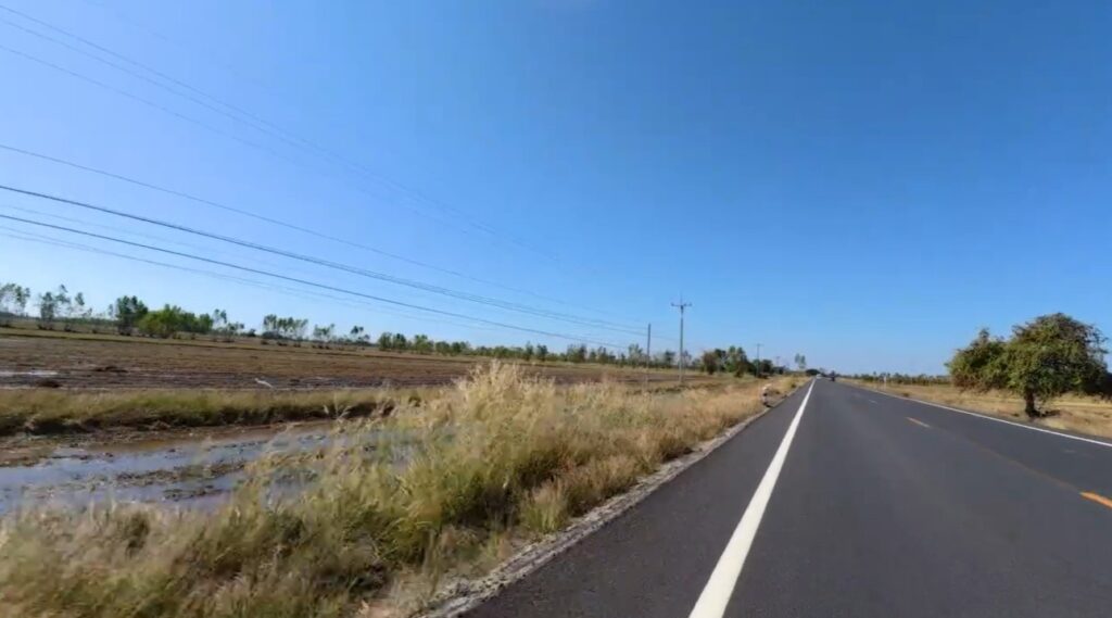 An empty rural road stretching across the wide plains of Isan between Buriram and Roi Et
