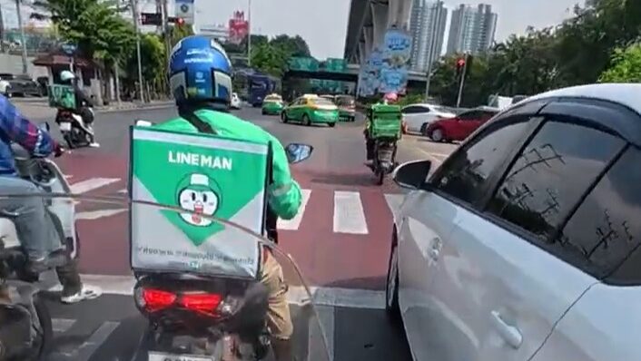 Beginner rider navigating heavy Bangkok traffic on a yellow Honda Cub