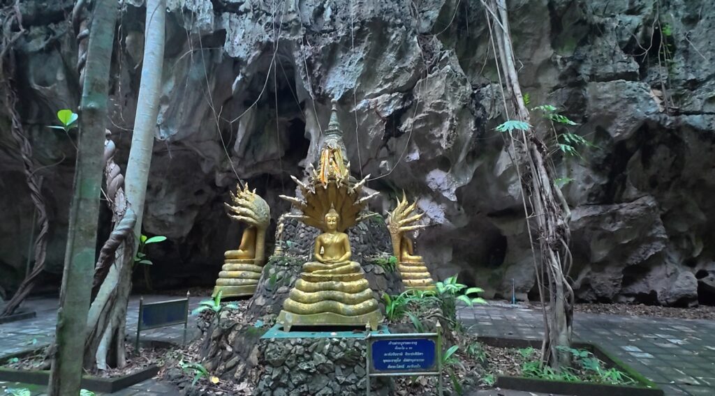 Small Buddhist chedi guarded by Naga figures inside a natural cave in Rayong