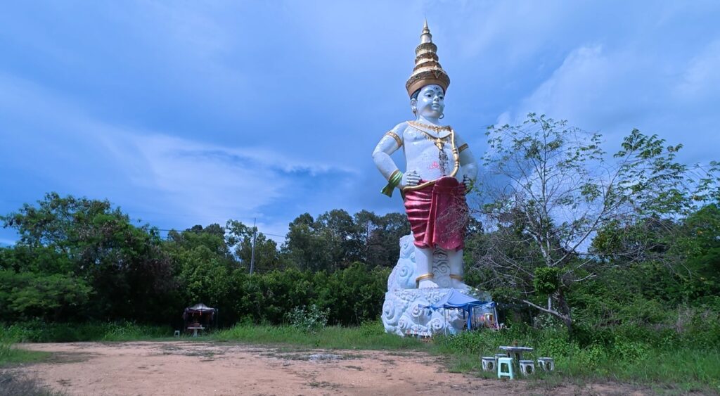 Tall local guardian spirit statue beside a rural road in Chonburi