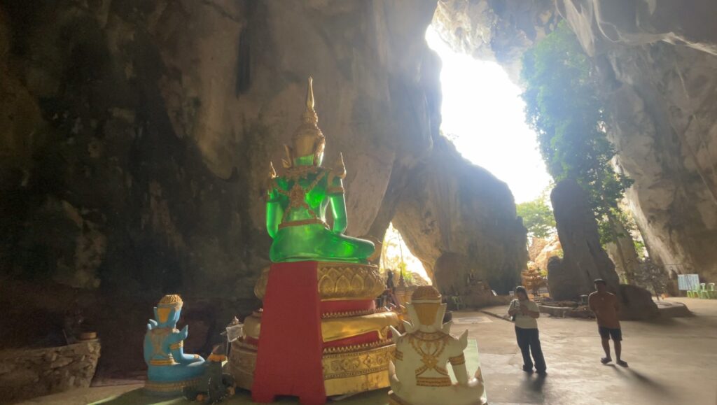 Buddha glowing with emerald-green light inside Tham Khao Bot cave