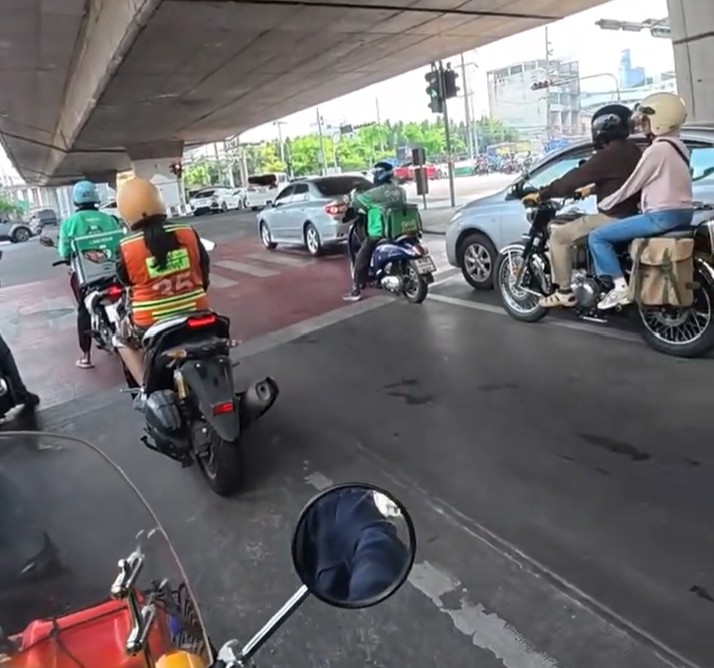 Honda Cub riding beneath an elevated road in heavy Bangkok traffic