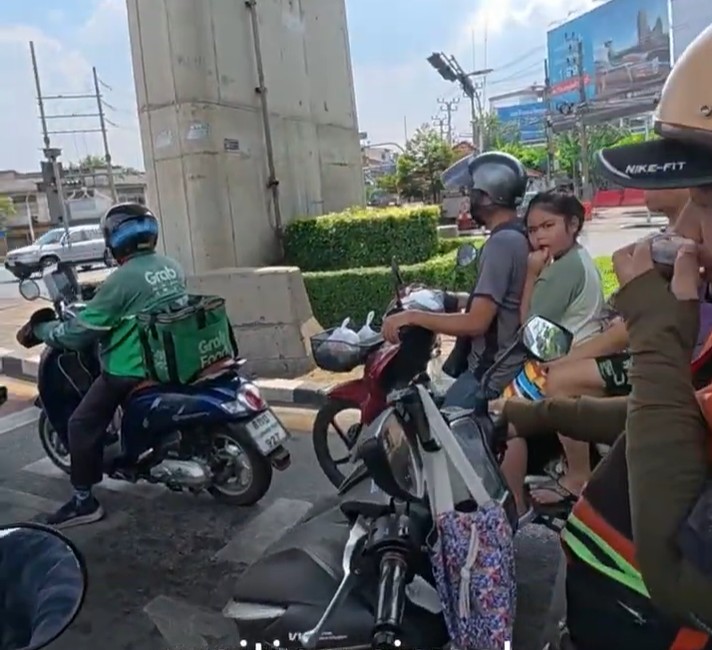 Yellow Honda Cub moving through dense traffic beneath Bangkok expressways