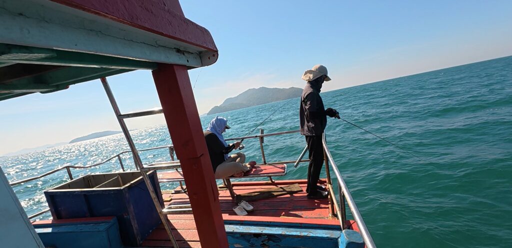 Friends waiting for a bite while sea fishing from a small boat