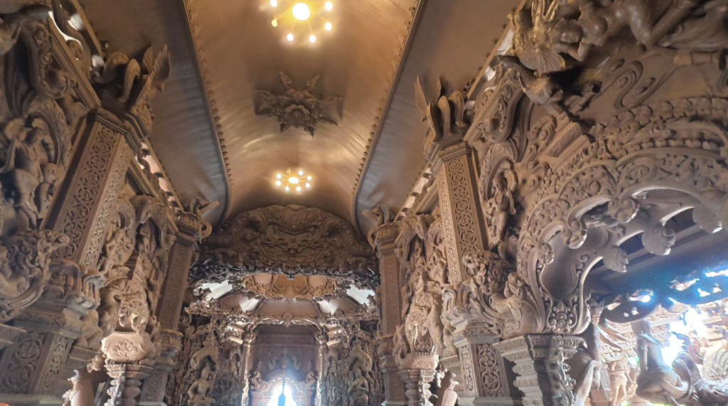 Interior hall filled with carved wooden pillars and religious sculptures inside the Sanctuary of Truth