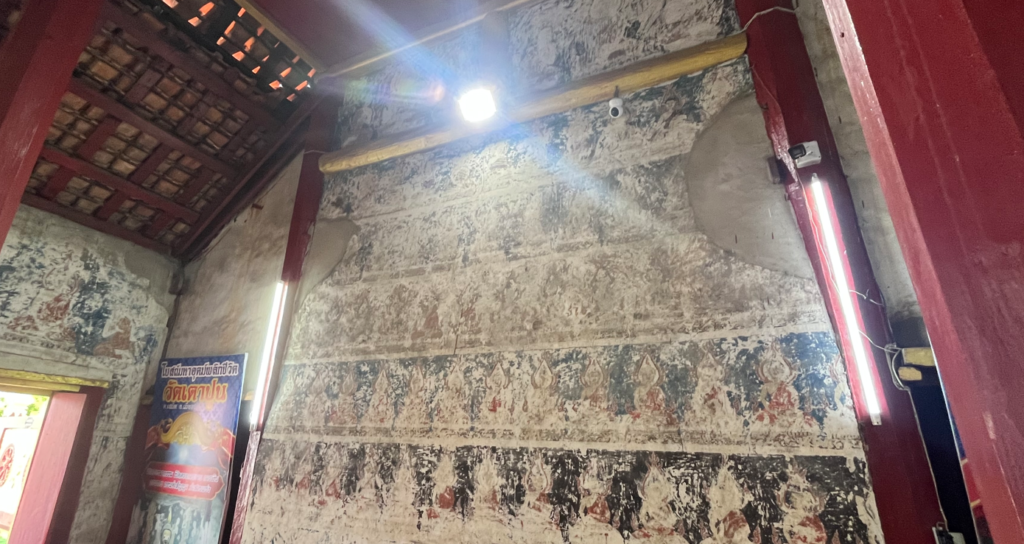 Rows of faded past Buddha murals inside Wat Tao Pun’s old ubosot