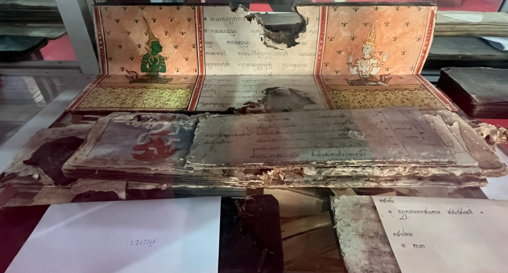 Writing and painted illustrations in a folding manuscript displayed at Wat Taphong Nai
