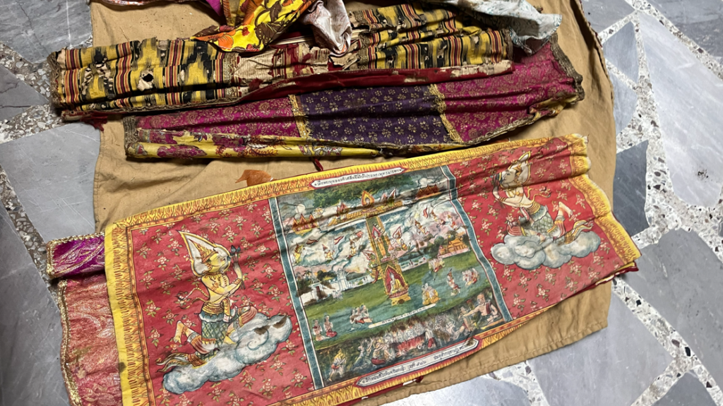 Colourful manuscript wrapping cloths at Wat Ban Laeng, including a red cloth decorated with Buddhist imagery.
